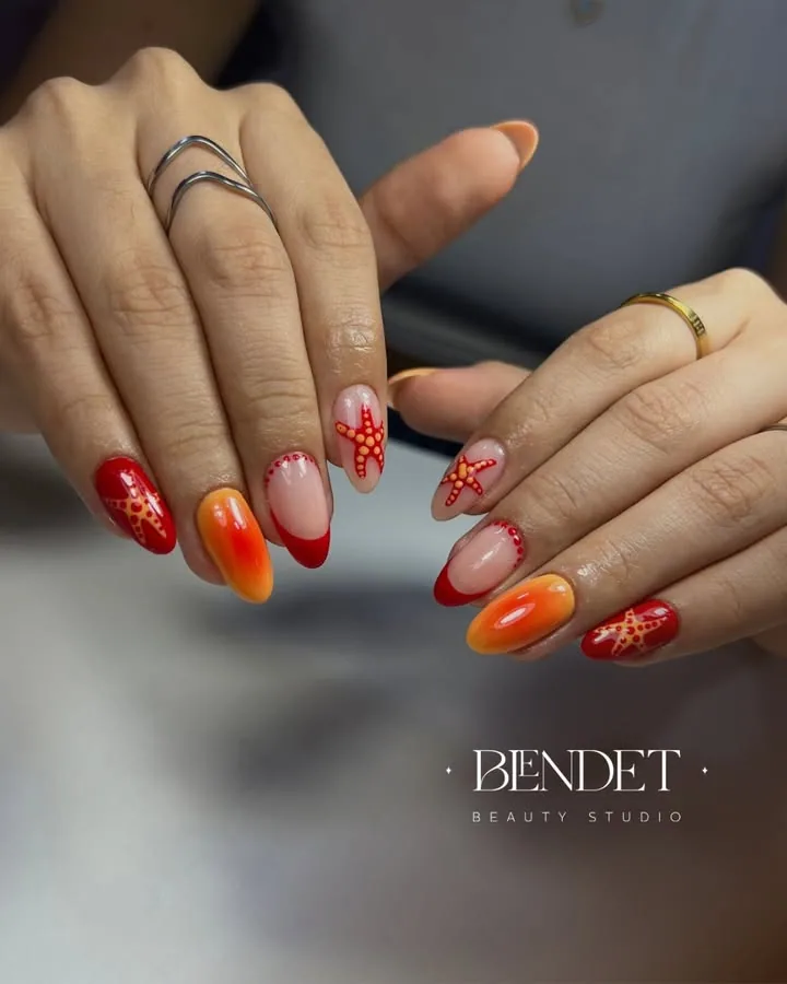 Uñas en degradé rojo y naranja con estrellas de mar